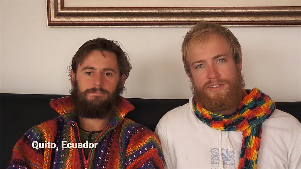 Two riders in Andean scarves and ponchos on a sofa. Caption: Quito, Ecuador.