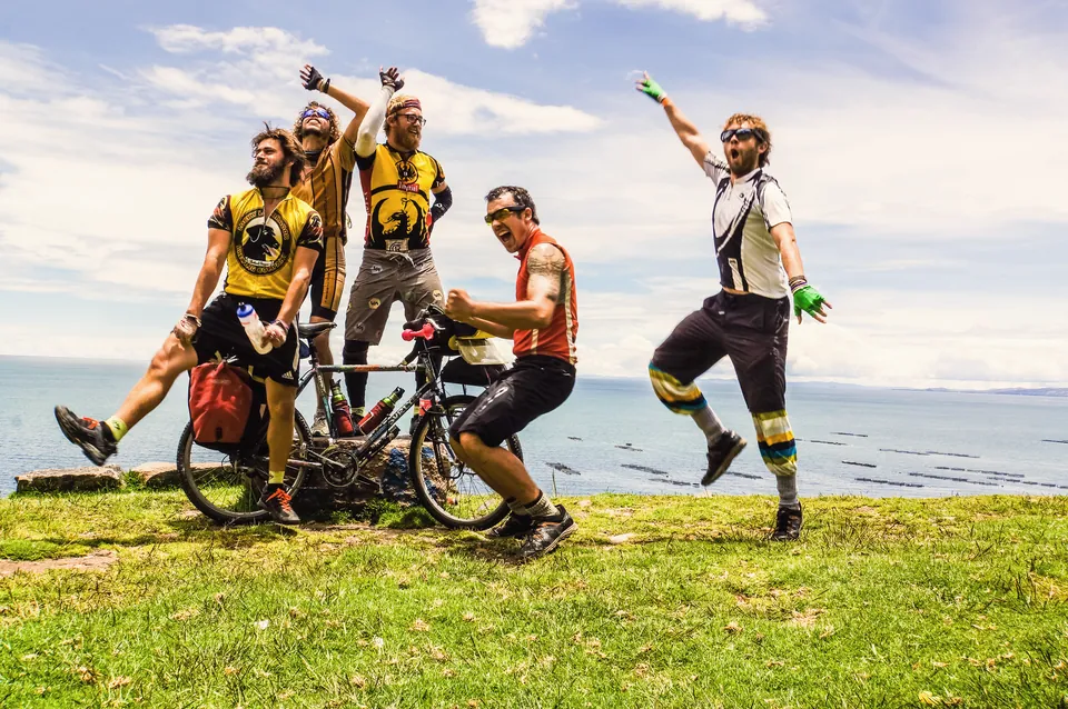 Five riders leaping and dancing on a bluff above Lake Titicaca.