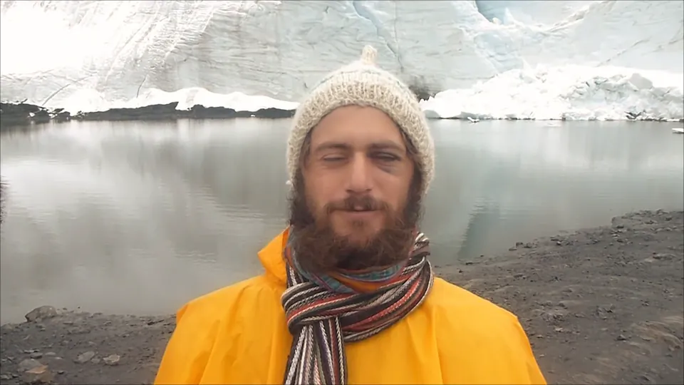 Boydy in a yellow jacket and woolly hat beside a glacier lake at five thousand metres.